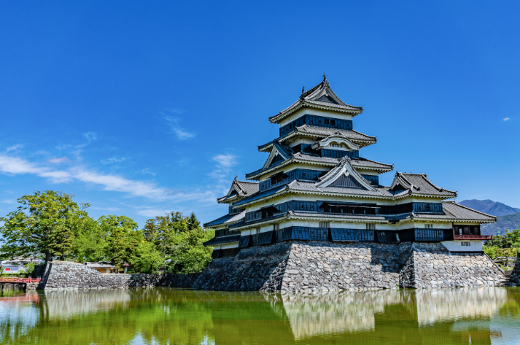 Matsumoto Castle, a Japanese castle situated on a lake, with mountains in the background