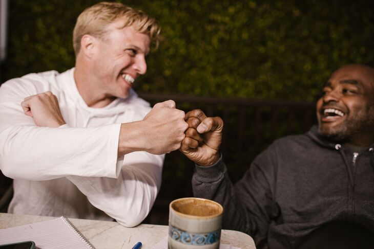 Two men fist bumping over a coffee
