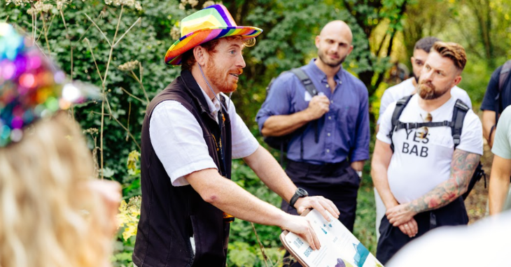 September 2026 top events in London: a person wearing a rainbow hat giving a talk to a small standing crowd, surrounded by trees