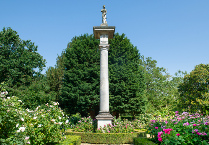 A stone column surrounded by flowers and greenery at Chiswick House and Gardens