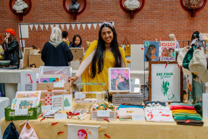 A trader posing for a photo behind her stall at a craft market