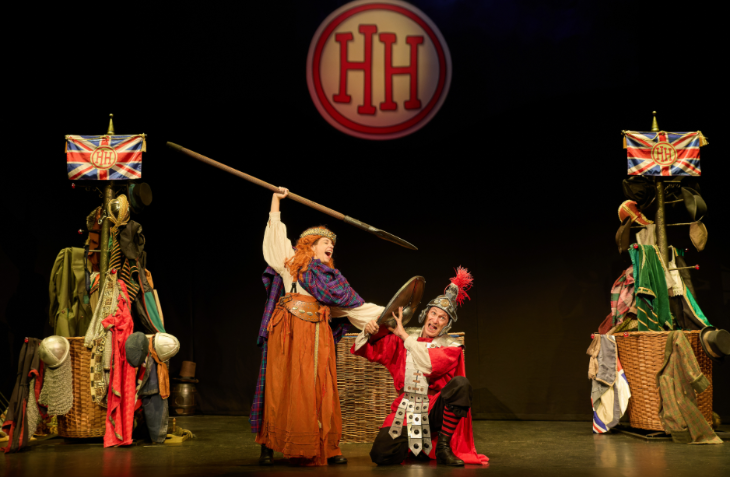 A scene from Horrible Histories on stage, featuring Boudica holding up a spear