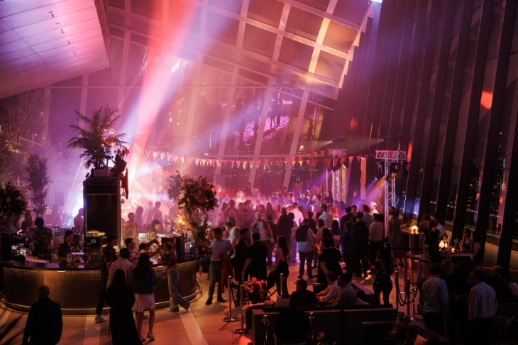 People dancing in the Sky Garden, which is illuminated with pink strobe lighting while it's dark outside