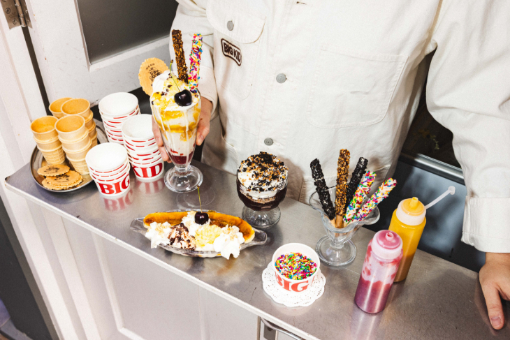 A metal counter with various ice cream pots, sauces and toppings