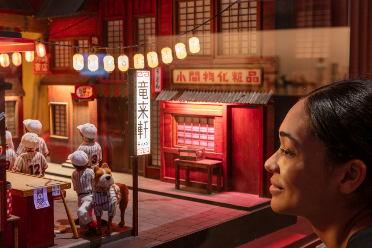 A woman face-to-face with a small street scene from Wes Anderson's Isle of Dogs