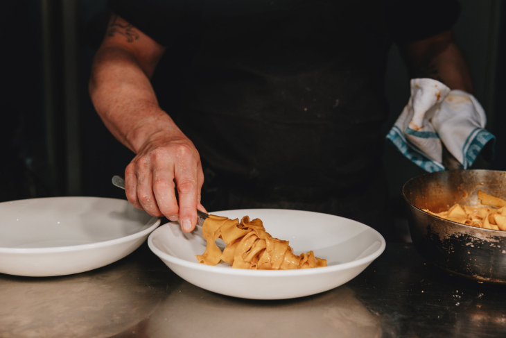 Things to do in London today: pasta being served into a bowl