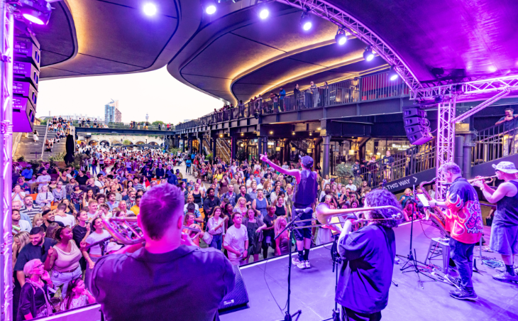 August 2026 in London: a view of a crowd watching musicians on a festival stage inside Coal Drops Yard