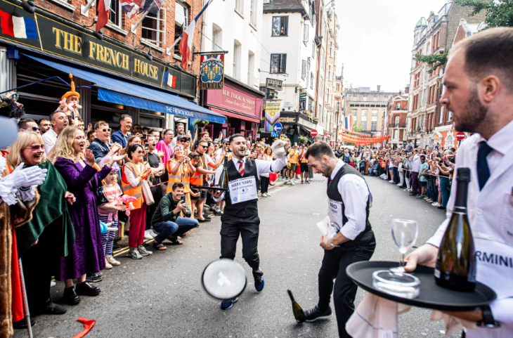 Waiters taking apart in the Soho Waiters' Race, cheered on by crowds outside the French House