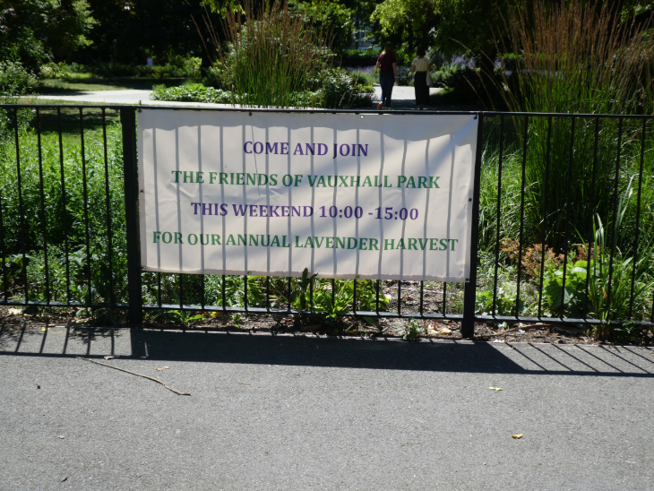 A banner on a fence reading "COME AND JOIN THE FRIENDS OF VAUXHALL PARK THIS WEEKEND 10:00-15:00 FOR OUR ANNUAL LAVENDER HARVEST"