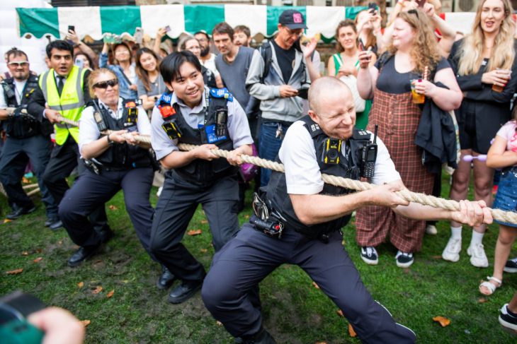 Police officers taking part in a tug of war, watched by crowds
