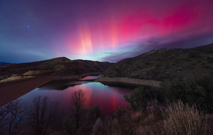 Pink Aurora lights over a body of water