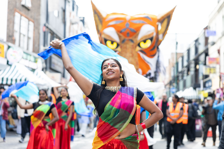 A bangra dancer with a huge tiger head looming behind her