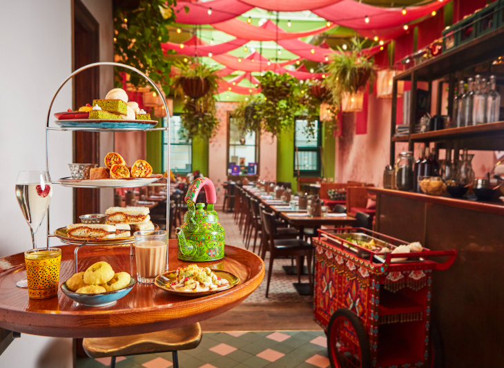 Best budget afternoon tea London: an afternoon tea stand on a table inside an otherwise empty colourful restaurant