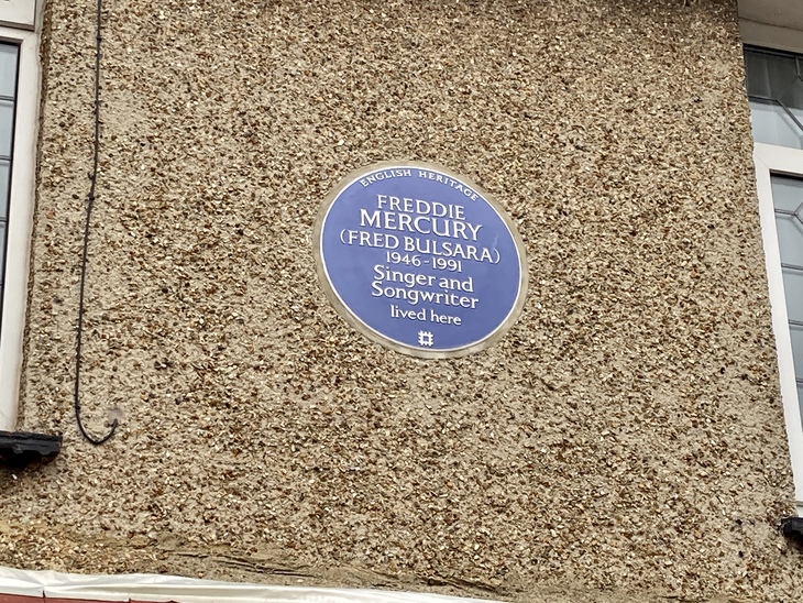 A blue circular English Heritage plaque on a pebbledash wall commemorates Freddie Mercury (Fred Bulsara), 1946-1991, singer and songwriter, who lived there.