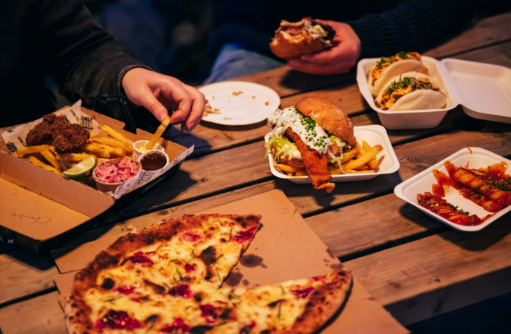 Hyde Park Winter Wonderland Christmas 2026 guide: A wooden table with takeaway food dishes including pizza and burgers