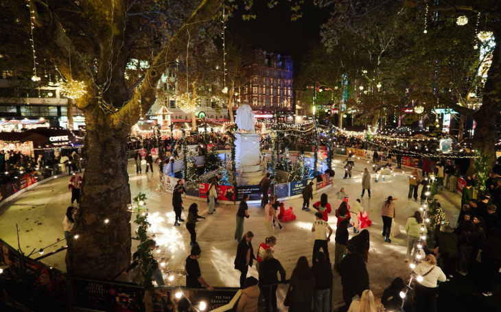 Where to go ice skating in London Christmas 2026: a photograph of people skating on a rink which encircles the Shakespeare statue in Leicester Square. It's night, and fairy lights are strung from the trees