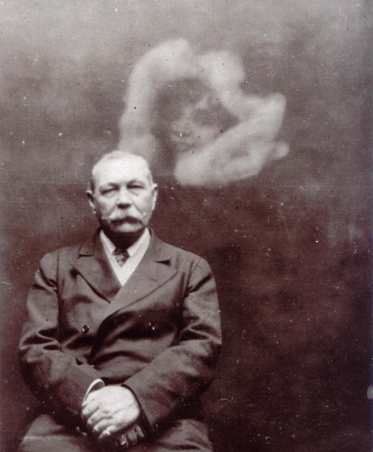 A sepia-toned vintage photograph of Sir Arthur Conan Doyle seated with his hands clasped, while a faint, ghostly image of a woman's face surrounded by white mist appears behind his shoulder.