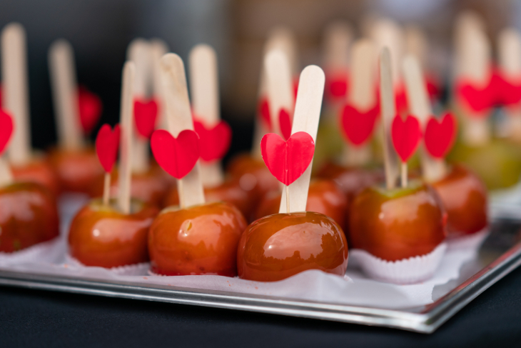 Things to do in London in October 2026: a tray full of toffee apples, their wooden stick decorated with red paper hearts