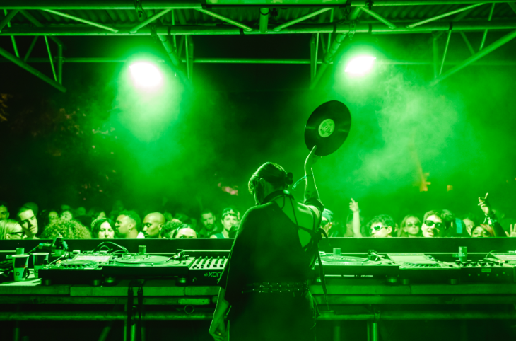 Things to do in London today: a green-lit photo of a DJ in front of a festival crowd