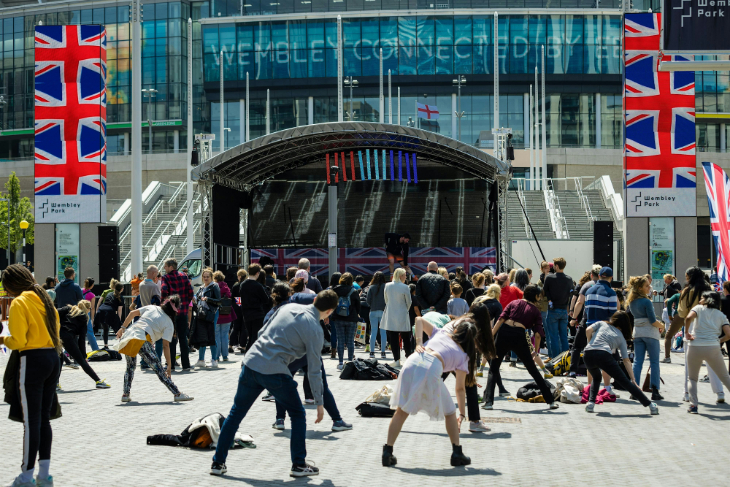 Things to do in London August bank holiday weekend 2026: people stretching in front of a pop-up stage in front of Wembley Stadium