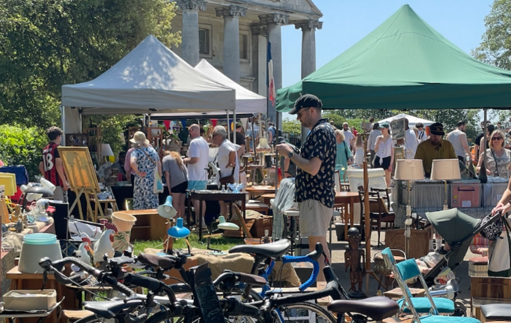 Things to do in London today: people wandering among stalls at an open-air vintage market in the sunshine