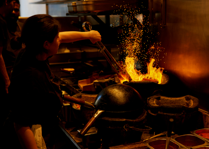 Things to do in London today: a chef cooking in a wok over live fire