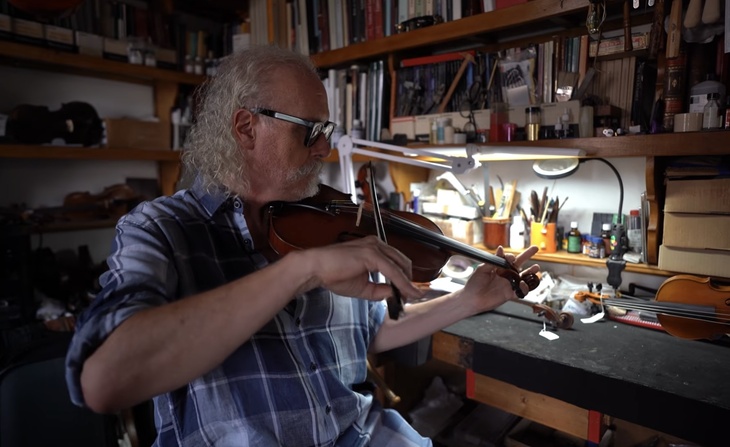 A man playing a violin in a workshop