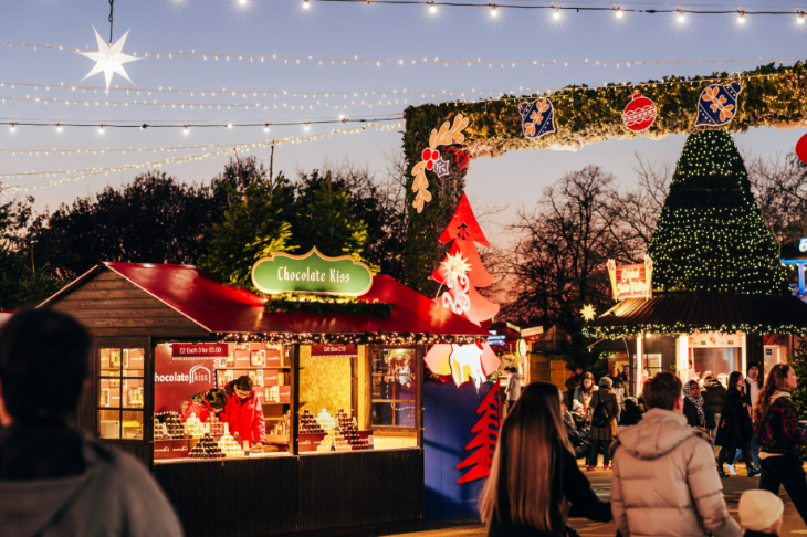 Hyde Park Winter Wonderland Christmas 2026 guide: People walking through a Christmas market at dusk