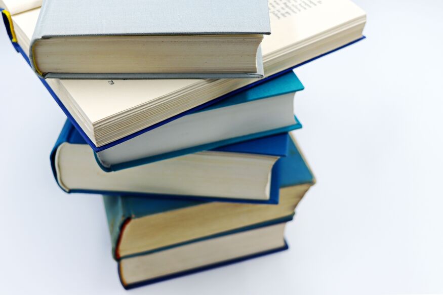 A stack of several thick, blue-bound books piled haphazardly on a white background.