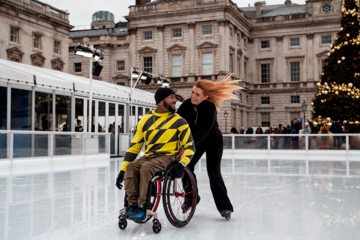 Christmas 2026 ice skating rinks in London: a woman pushing a man in a wheelchair around an ice skating rink at Somerset House 