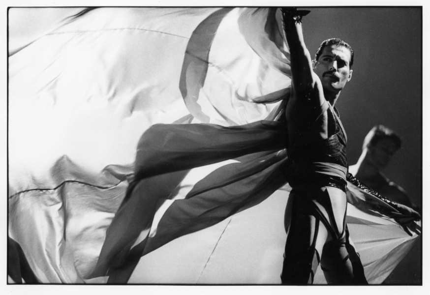 Black and white photo of Freddie Mercury swishing a cloak behind him