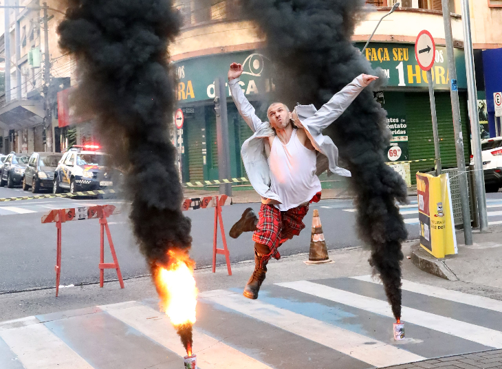 A performer dancing between flames and plumes of smoke on a street scene film set