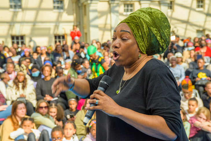 A woman holding a microphone and talking in front of a crowd of people at the National Maritime Museum