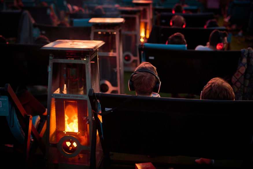 Halloween 2026 film screenings London: people sitting in deckchairs alongside fire lamps watching a film on a large screen at an open-air cinema