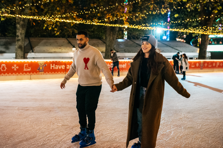 Ice skating in London for Christmas 2026: a couple holding hands and ice skating on an outdoor rink