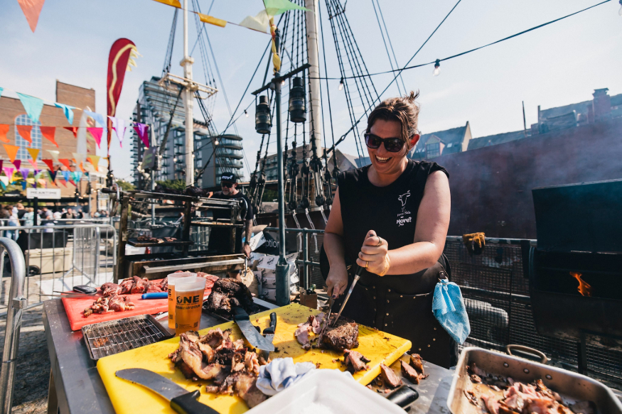 Things to do in London this weekend: a woman slicing cooked meat in the open-air, in front of what looks like a pirate ship