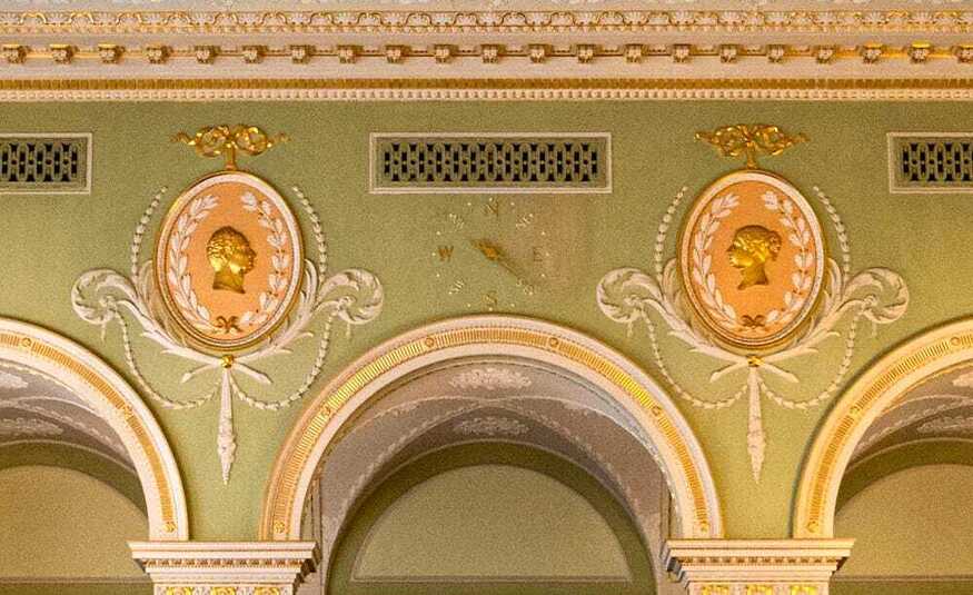 A detail of a wall showing a clock and ventilation