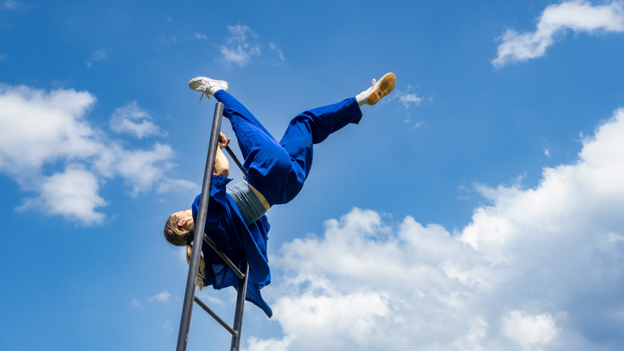Things to do in London this weekend: a performer wearing blue hanging upside down from a ladder in the sky
