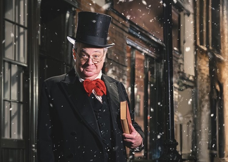 A rather jolly looking Scrooge in a stovepipe hat