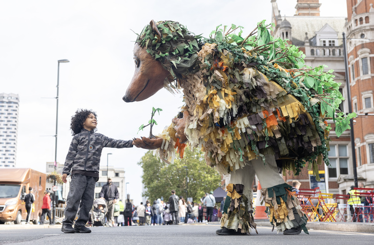 A young child with a huge hedgehog puppet