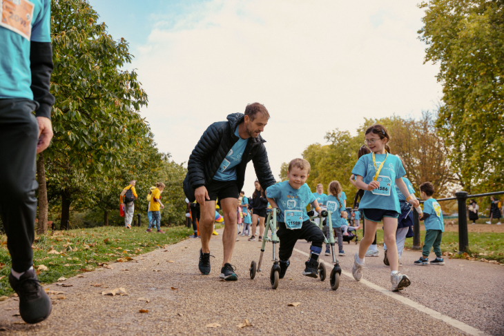 A young boy doing a walk, helped on by others