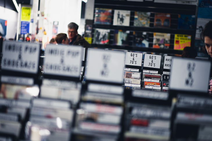 A shallow-depth-of-field shot inside a record store, focusing on white genre labels like 