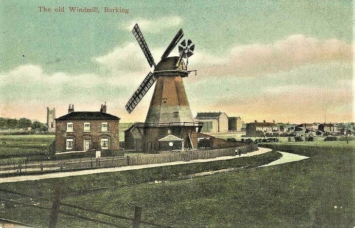 A vintage color postcard titled The old Windmill, Barking, showing a tall smock windmill and a two-story brick house in a grassy field.