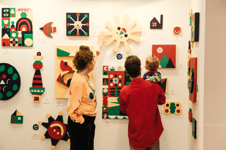 Things to do in London today: two adults and a child looking at a display of artwork on a wall
