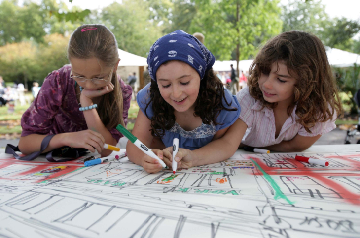 Things to do in London this weekend: three children leaning over a piece of paper and drawing/colouring