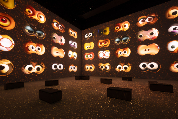 Pairs of eyes belonging to Aardman characters peeking out on a large projection wall at Lightroom