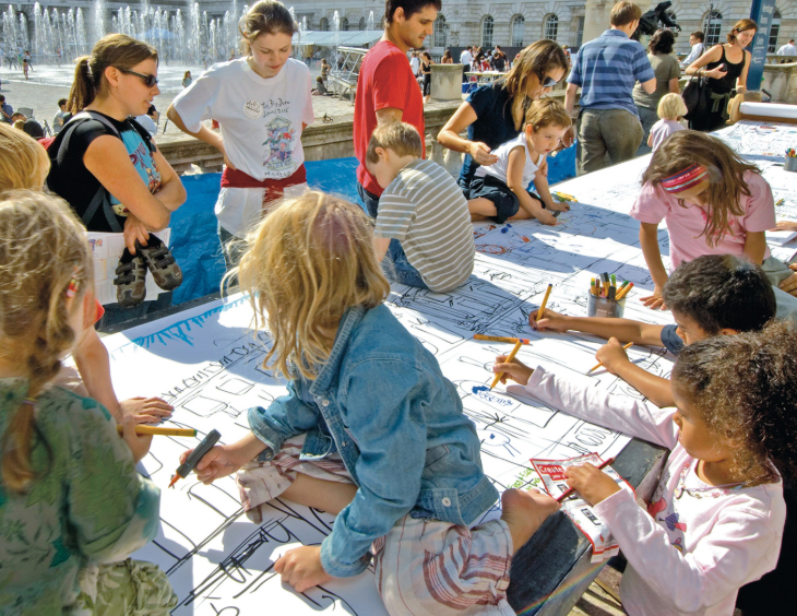 Things to do in London today: children drawing and colouring on a large mural laid out on a table