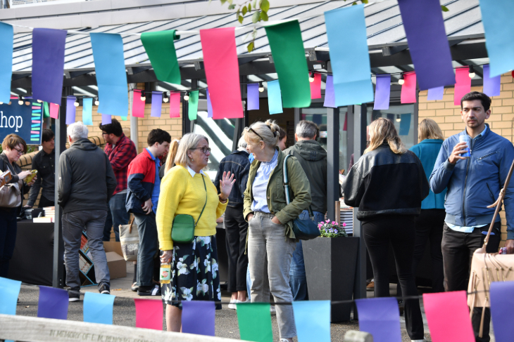People standing and chatting beneath colourful bunting