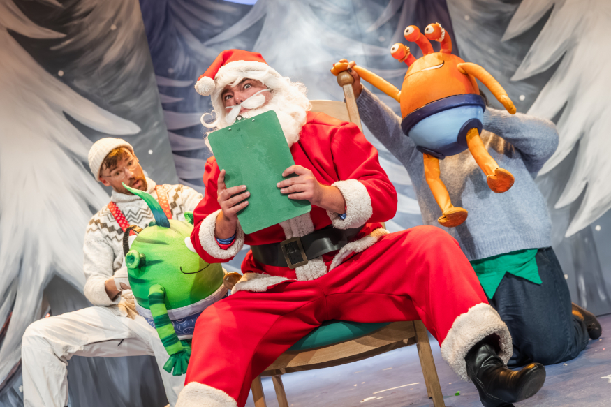 Family Christmas theatre shows 2026: Santa Claus sitting on a chair holding a clipboard, surrounded by aliens
