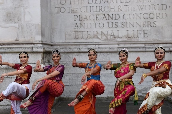 South Asian women dancing in front of a monument